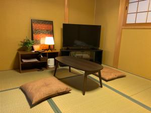 a living room with a television and a coffee table at KYOTO SHIMA in Kyoto