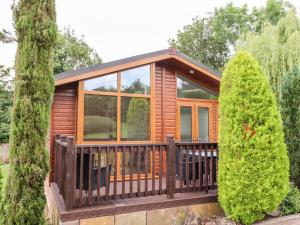 een hut in het bos met een terras en bomen bij Oak Lodge in Longhope
