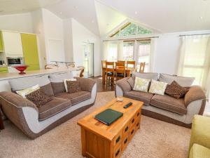 a living room with two couches and a table at Oak Lodge in Longhope