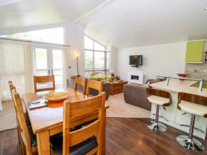 a kitchen and living room with a table and chairs at Oak Lodge in Longhope