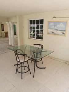 a glass table and two chairs in a room at Grace Garden Guesthouse in Ocho Rios