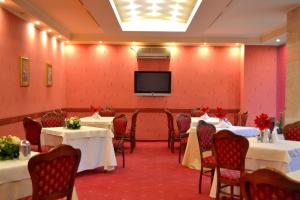 ein Bankettsaal mit Tischen und einem Flachbildfernseher in der Unterkunft Hotel Tiara in Ploieşti