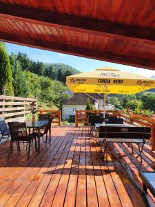eine Terrasse mit Tischen, Stühlen und einem Sonnenschirm in der Unterkunft Pensiunea Casa Motilor in Bucium