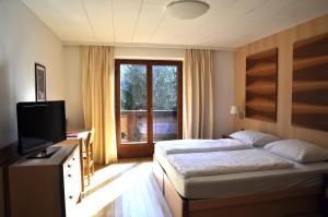 a bedroom with two beds and a television and a window at Hotel Piné in Tires