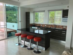 a kitchen with a black counter and red stools at Chiang Khan Riverside Pool Villa in Chiang Khan