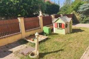 un patio trasero con una casa de juguetes y una valla en Villa Tátika en Gárdony