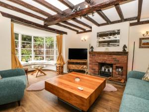 a living room with a table and a fireplace at Eleri Cottage in Great Malvern