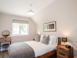a bedroom with a bed with white sheets and a window at The Loft in Spean Bridge