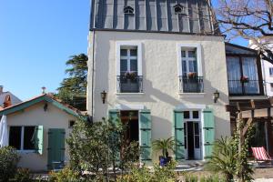 uma casa branca com persianas verdes em Villa Kumquats em Béziers