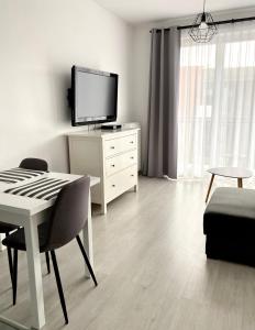 a white living room with a table and a tv at Apartament Bastion Wałowa in Gdańsk