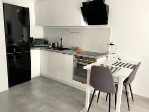 a kitchen with white cabinets and a white table and chairs at Apartament Bastion Wałowa in Gdańsk