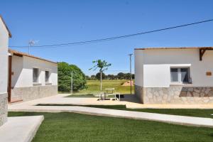 une maison blanche dotée d'une cour verdoyante avec un banc dans l'établissement ALAMANCHA, à Casas de los Pinos