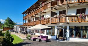 a hotel with a patio with purple chairs and an umbrella at Das Alpensee in Unterburg am Klopeiner See