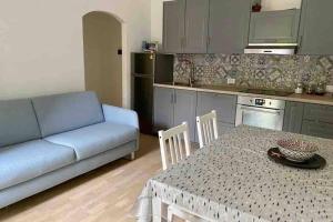 uma sala de estar com um sofá, uma mesa e uma cozinha em Piazza Anco Marzio fronte mare casa con giardino em Lido di Ostia