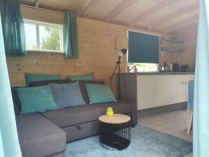 a living room with a couch and a kitchen at Tiny house op wielen Friesland in Workum