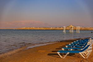 a row of beach chairs sitting on top of a beach at Daniel Dead Sea Hotel in Ein Bokek