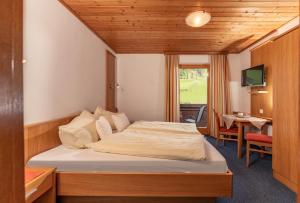 a bedroom with a bed and a desk and a television at Gästehaus Huber Frühstückspension in Schladming