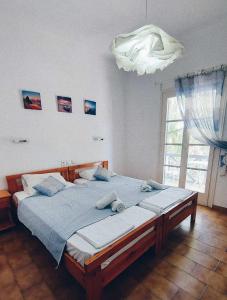 a bedroom with a bed with blue sheets and a window at Nefeli rooms Ios in Ios Chora
