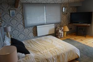a bedroom with a bed and a flat screen tv at La Marlière Chambre de Charme in Houthem