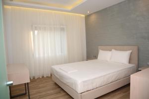 1 dormitorio con cama blanca y ventana en Coral Boutique Apartments, en Ofrinion