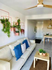 uma sala de estar com um sofá branco e plantas na parede em Homing La Pineda 23 em La Pineda
