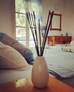 a white vase sitting on a table next to a bed at Nefeli rooms Ios in Ios Chora