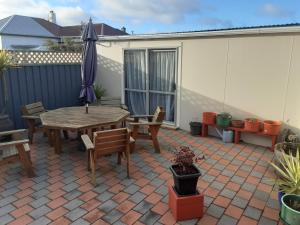 a patio with an umbrella and a table and chairs at I'm a traveller in Dunedin