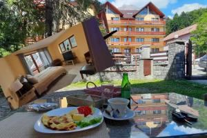 a table with a plate of food and a cup of coffee at Kalinderu SKIER'S APARTAMENT BELLEVUE in Buşteni