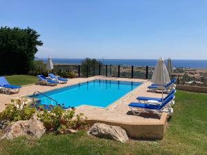 una piscina con tumbonas y sombrillas en Villa Amadeus, en Kalathos