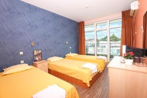 a room with three beds and a blue wall at La Piazza Family Hotel in Sunny Beach +31 photos