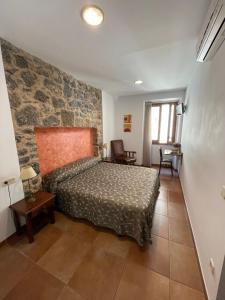 a bedroom with a bed and a stone wall at Fonda Mitjà in Torroella de Montgrí