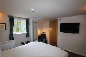 a bedroom with a white bed and a flat screen tv at rooms @ the dolau inn in New Quay