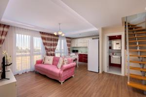 a living room with a pink couch and a kitchen at Onix Apart Hotel in Antalya