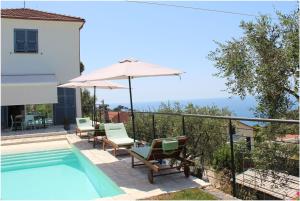 a pool with chairs and an umbrella next to a house at Il Sole di Poggi in Imperia