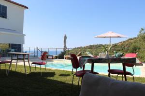 a table with chairs and an umbrella next to a pool at Il Sole di Poggi in Imperia