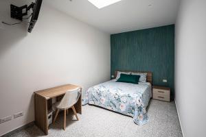 Schlafzimmer mit einem Bett, einem Schreibtisch und einer grünen Wand in der Unterkunft Mola’s Square House in Mola di Bari