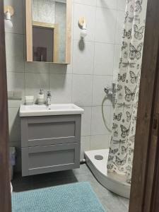 a bathroom with a sink and a shower curtain at Laumžirgių upė - jaukus butas ramiam poilsiui Anykščiuose in Anykščiai