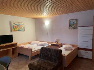a bedroom with two beds and a chair and a desk at Apartmenthaus Punta **** in Splitska