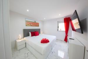 biała sypialnia z białym łóżkiem z czerwonymi poduszkami w obiekcie MEDANO4YOU The Austrian Holiday Home w mieście El Médano