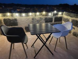 two chairs and a table on a balcony at night at INSOLITE STUDIO -La Tour des Templiers- in Montfrin