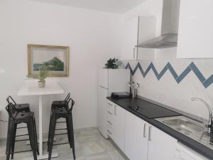 kuchnia z dwoma czarnymi stołkami i lodówką w obiekcie Apartamentos Sanlúcar Beach 2 y 3 w mieście Sanlúcar de Barrameda