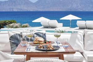 a table with a plate of food and glasses of wine at The Island Concept Luxury Boutique Hotel Heated Pool in Agios Nikolaos