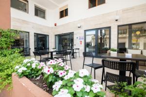 a patio with tables and chairs and flowers at Hotel De Plam in Olbia