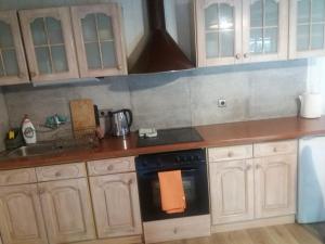 a kitchen with wooden cabinets and a black stove top oven at Domek Sara in Przytarnia