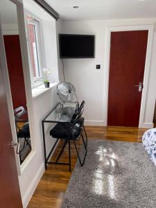 a room with a glass table and a tv on a wall at Adorable Guest house in Erith