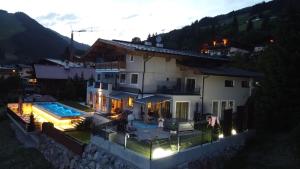 una grande casa bianca con piscina di notte di Appartements Casa Nuova a Saalbach Hinterglemm