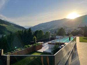 uma vista para uma casa com piscina e montanhas em Appartements Casa Nuova em Saalbach Hinterglemm