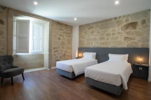 a hotel room with two beds and a chair at Solar Valadim - serviced apartments in Castelo Branco