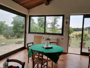 a dining room with a green table and some windows at Predio Potantino in Proceno