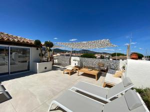 un patio con sillas blancas y una mesa en el techo en Lostane - Villa sur le toit, en Grimaud